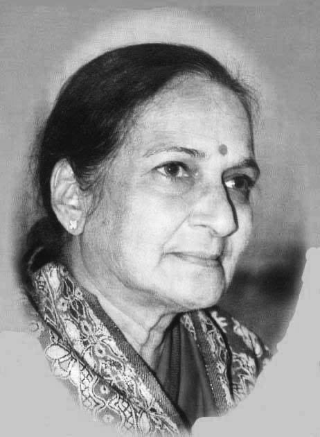 Black-and-white portrait of Rau Balasaraswati Devi, an elderly woman with hair in a bun, wearing a sari with intricate patterns, earrings, and a bindi on her forehead, smiling gently while looking slightly to the side.