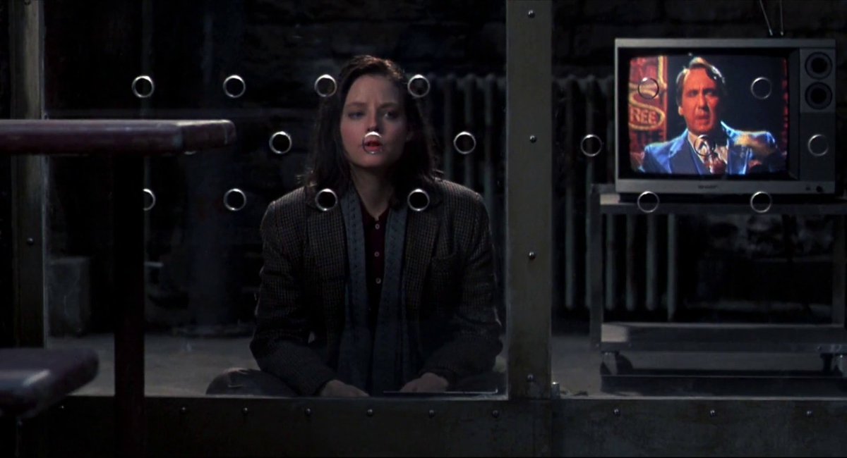 Muy interesante el punto de vista y la puesta en escena en las celdas con Lecter en 'El silencio de los corderos'. Ej.: este plano donde se coloca al mismo nivel compositivo y de significado a Clarice y a la TV: para Hannibal, ella no es más que otro divertimento al que mirar.