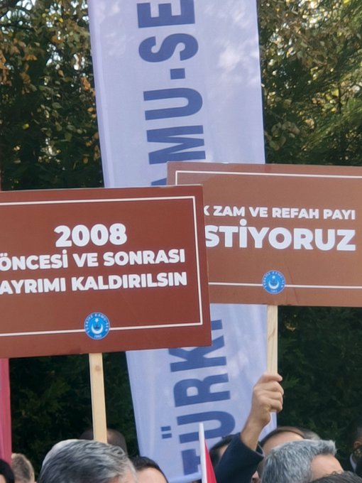 First image shows a large group of men in suits and ties gathered outdoors near trees, holding red banners with white text reading MAASLARDA REFORM YAP and ADALET, surrounded by microphones and cameras from media, with Turkish flags and union banners in the background. Second image displays two brown posters side by side, one marked 2008 with text ZAM VE REFAH PAYI ÖNCESI VE SONRASI AYIRIMI KALDIRILSIN, the other with similar content, held by individuals near blue Türk Sağlık-Sen flags and a Turkish flag. Third image features a black-framed white sign held by a man, reading 8 EK GÖSTERGE BORÇDURO ŞAKA GİBİ AMA GÜLEMIYORUZ, with a blue union logo, next to a red Turkish flag and other protesters. Fourth image depicts people in blue vests and suits holding brown banners stating CON MAZANANDAN AZ KAZANANDAN ÇOK VERGİ AL VERCH, with Turkish flags and additional protest signs in a green outdoor setting.