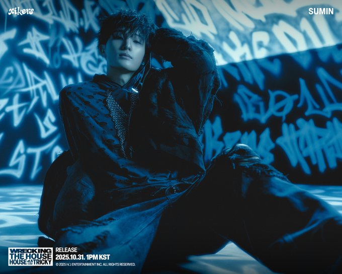 First image shows Sumin wearing a dark blue hooded jacket and pants sitting on the ground against a blue-lit graffiti wall with Korean text XIKERS at top and bottom, hand raised to head, phone in hand, text overlay HOUSE OF TRICKY WRECKING THE HOUSE 2025. 10. 31. 1PM(KST) RELEASE. Second image is a close-up of Sumin face with intense expression, dark hair, blue lighting, same text overlays including XIKERS and concept poster title for Sumin.