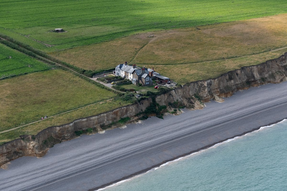 johnfielding001's tweet image. Weybourne Coastguard Cottages, Norfolk - aerial view. Built early 1900s to house HM Coastguard on a deep-water, smuggling-prone stretch at Weybourne Hope. Now private/holiday lets; active cliff erosion gives them a finite future #Norfolk #cliffs #erosion #aerial #image #coast
