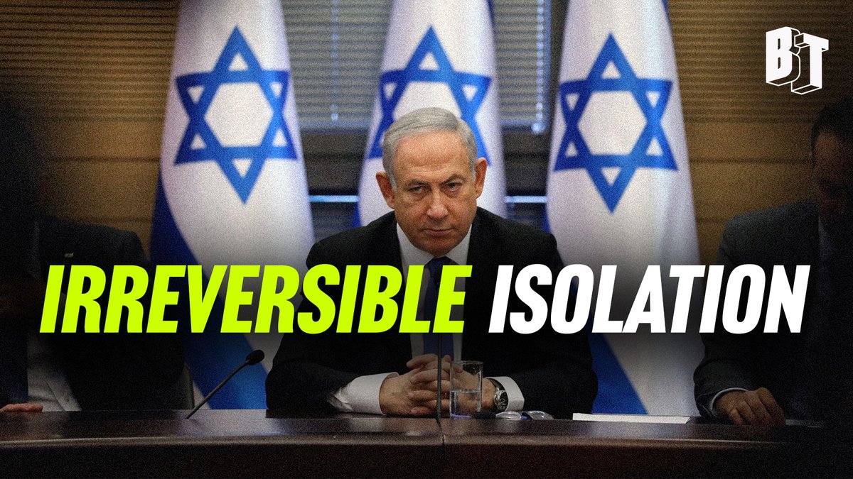 Three Israeli flags stand behind a wooden table in a formal room with large windows. Benjamin Netanyahu sits at the center in a dark suit, looking serious with hands clasped. Two other men in suits sit beside him. A microphone is on the table. Yellow text overlay reads IRREVERSIBLE ISOLATION in bold letters. BreakThrough News logo appears in the corner.