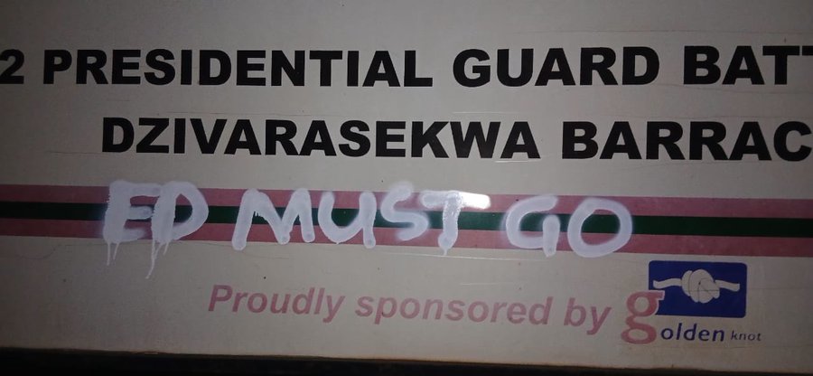 A horizontal signboard for the 2 Presidential Guard Battalion at Dzivarasekwa Barracks with green and pink stripes and a sponsor logo for Golden at the bottom, overlaid with white graffiti text reading ED MUST GO.
