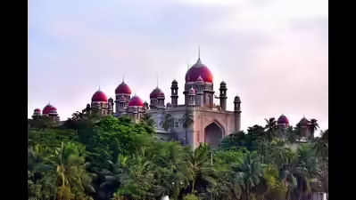 A large historical building with multiple red-domed towers and arched facades stands prominently against a partly cloudy sky surrounded by lush green trees and palm foliage in a natural setting.