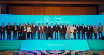 First image shows a large group of formally dressed men and women standing side by side on a stage with blue backdrop displaying Canva İş Birliği Protokolü Tanıtım Toplantısı text and Turkish flag emblem. Second image depicts a man in suit speaking at a white podium with microphone, large Canva logos on blue screens behind, another suited figure visible on a screen. Third image features a bald man in suit at a podium with microphone, Canva branding on screens, ornate room setting with blue lighting. Fourth image captures a panel of six people in business attire seated at a table on stage with blue Canva backdrop announcing 16 Ekim 2025 Ankara event, including men and women some wearing headscarves.