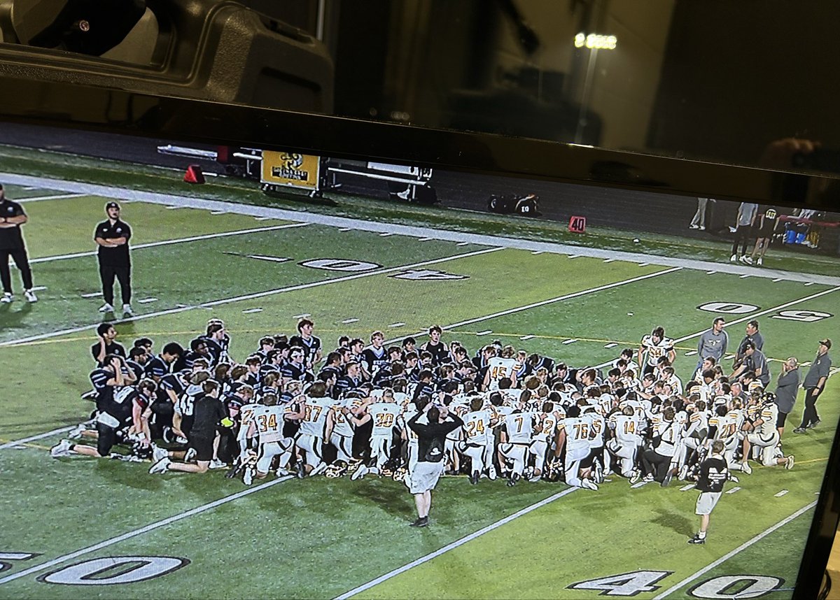 Great scene here in Elkhorn. Both teams at midfield in prayer for the family of Elkhorn North Head Coach Sam Stanley.