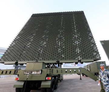 First image displays the national flag of China with a large yellow star in the upper left corner and four smaller yellow stars arranged in an arc to its right on a solid red background. Second image shows a large rectangular phased array radar antenna covered in a grid of small elements mounted on top of a green military truck with six wheels and a camouflage-patterned uniform visible in the foreground on a paved outdoor area.