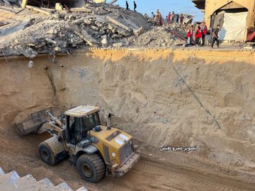 First image shows diverse group of aid workers including women and men in red vests with IRC patches walking through rubble-strewn street amid collapsed buildings and debris under clear sky with onlookers in background. Second image depicts yellow bulldozer excavating large pile of concrete rubble next to damaged structures with several people in red vests standing on elevated debris observing the clearing operation.
