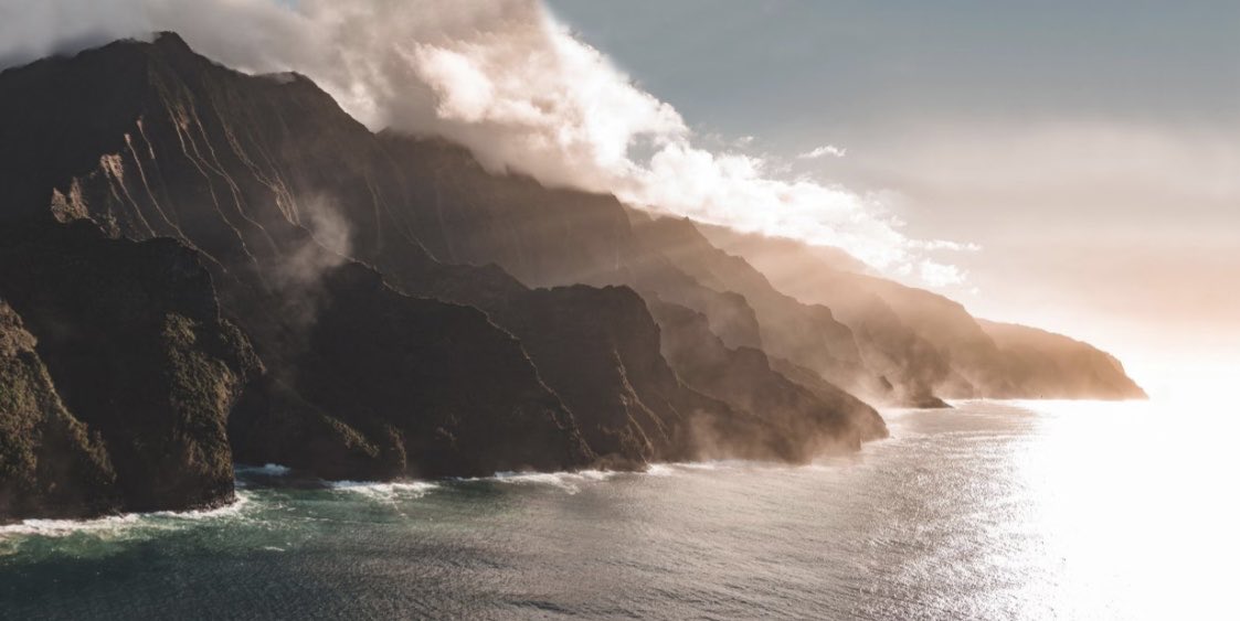 Selim Cinek’in Hawaii’de çektiği bu fotoğrafa vuruldum. Güneş ışınları sanki dağı aşındırıp suya karıştırırken karanlık ve soğuk ağırlığına tezat yumuşak ama bir o kadar yoğun bir bulut adeta yatak örtüsü gibi üstüne çekiliyor. Absürtlük çarpıyor insana.