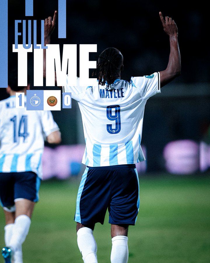 Player Fiston Mayele with dreadlocks raises both arms in celebration on a green soccer field at night, wearing a white and light blue Pyramids FC jersey with number 9 on the back, dark blue shorts, and white socks with light blue accents. Another player in a dark blue jersey with number 14 stands nearby on the field. Full Time graphic overlay in light blue shows score 1-0 with Pyramids FC logo.