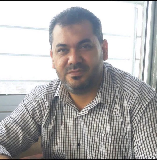 First image shows a man in a light brown suit white shirt and red striped tie smiling in a hospital setting with Arabic signs on walls including one reading Nasser Hospital and blue banners with medical symbols. Second image depicts the same man wearing a checkered shirt smiling while seated near a window with white blinds in an indoor environment.