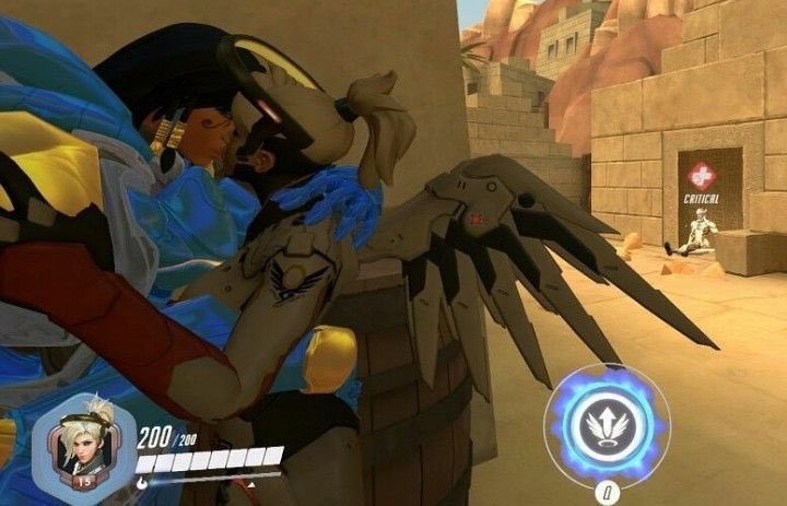 Screenshot of Pharah and Mercy in a game, sort of, embracing and kissing each other near a wall. In the distance, Genji is seen sitting down with a red “critical” health indicator.