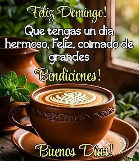 A terracotta cup with intricate patterns holds a latte topped with leaf-shaped foam art. Green plants and leaves surround the cup on a wooden surface. Another terracotta pot is visible nearby. Text overlays include Feliz Domingo at the top left Que tengas un dia hermoso Feliz colmado de grandes Bendiciones in the middle and Buenos Dias at the bottom right.