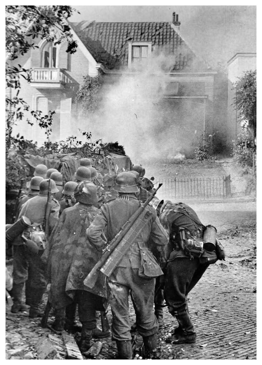 Soldados de infantería del Heer. Esperan parapetados detrás de un muro. Han lanzado granadas contra la casa situada en frente de ellos. Está ocupada por tropas paracaidistas británicas. Operación Market Garden. 24 de septiembre de 1944. Oosterbeek. Países Bajos.