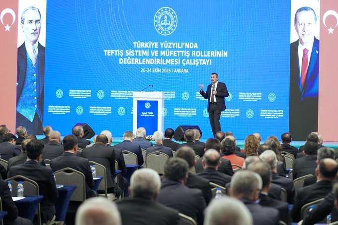 First image shows a man in a suit speaking at a podium on a stage with Turkish flags, the Ministry of National Education emblem, and large screens displaying portraits of Mustafa Kemal Atatürk and Recep Tayyip Erdoğan, banners reading Teftiş Sistemi ve Müfettiş Rollerinin Değerlendirilmesi Çalıştayı, and an audience seated in chairs. Second image depicts an overhead view of a large conference hall with a blue-themed stage, multiple flags including Turkish and organizational banners, rows of attendees in suits seated at tables with water bottles, and ornate wooden paneling on walls. Third image captures a wide group photo of numerous professionals in business attire seated in rows on a stage with a central table holding flowers and water glasses, surrounded by chairs and a backdrop of wooden architecture and lighting.