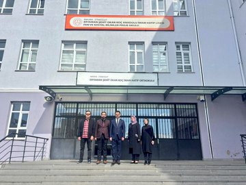 First image shows a group of women in headscarves and professional attire seated around a conference table in a bright classroom with windows and cabinets, engaged in discussion with a man standing and speaking. Second image depicts a man in a suit standing and addressing female students in headscarves seated at wooden desks in a classroom with white curtains and windows. Third image captures a diverse group of male and female students and staff, some in headscarves, standing together in a classroom near desks and a whiteboard. Fourth image features five individuals, including men in suits and women in headscarves, posing in front of a school building entrance with signage for Pen Sosyal Kulup Anadolu Imam Hatip Lisesi.
