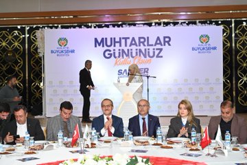 Multiple images show formal indoor events with groups of men and women in suits and dresses seated around round tables covered in white cloths with red runners, featuring plates of food, water bottles, and Turkish flags. Attendees engage in discussions, some standing at podiums or near banners reading Muhtarlar Günü and Malatya Büyükşehir Belediyesi. A young girl in a purple dress sits among adults in one scene, and another image includes a child interacting with participants. Backdrops include decorative elements like flowers and event logos. All scenes depict professional gatherings without additional visible objects.