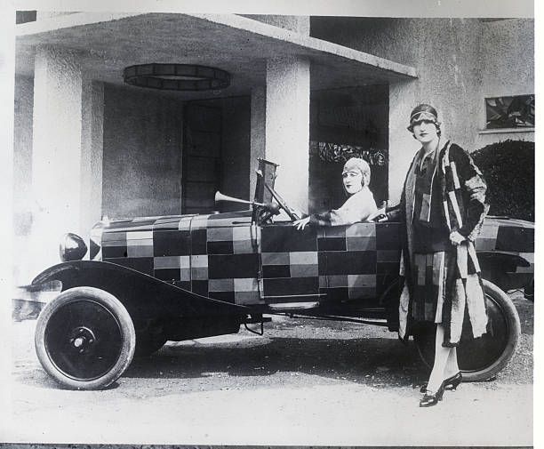 Oct. 20, 1925: “One of the new smart automobiles shown at the exposition building in Paris.” Both the car and the clothes of the model standing by it are designed by Sonia Delaunay, who uses “simultanism,” or interlocking color contrasts, as the basis of her patterns.