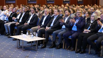 First image shows a man in a dark suit with glasses standing at a white podium labeled BAYINDIR MEMUR-SEN, gesturing with his right hand while speaking into a microphone, with a large blue screen behind displaying BÜYÜK KURULTAY 19-21 EYLÜL and a logo. Second image depicts a large audience of men and women in formal attire seated in rows on blue chairs in a conference hall, clapping and listening attentively, with a small table holding water glasses in the foreground. Third image features a man in a suit speaking at a podium with the Turkish flag and another emblem on screens showing crowded audience images and text like BÜYÜK KURULTAY. Fourth image shows a speaker in a suit at a white podium addressing a large seated audience in suits in a carpeted hall with Turkish flags and banners on walls.