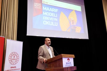 First image shows a man in suit speaking at podium with microphone in conference hall screen displays Turkiye Yuzyili Maarif Modeli and Hayat Boyu Ogrenme logos banners with Bingol University emblem and Turkish flags visible. Second image depicts large group of men and women in formal attire seated in auditorium rows some wearing headscarves table with white flowers and water glasses in front. Third image features diverse group of young women and men standing on stage in casual and formal clothes behind screen showing Ale Konferanslari Bingol logo. Fourth image portrays two men in suits one presenting plaque to the other on wooden floor against dark background with screen showing emblem.