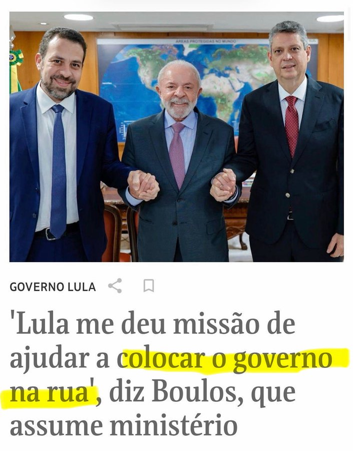 Three men in suits stand side by side in a formal room with overhead lighting and a large world map on the wall behind them the man on the left has short dark hair wears a blue suit white shirt and blue tie the central man is bald with a beard wears a blue suit white shirt and blue tie the man on the right has short dark hair wears a dark suit white shirt and red tie they hold hands in a gesture the text overlay in red reads Lula me deu missao de ajudar a colocar o governo na rua diz Bolsonaro que assume ministerio with highlighted sections governo Lula and governo Lula below the text