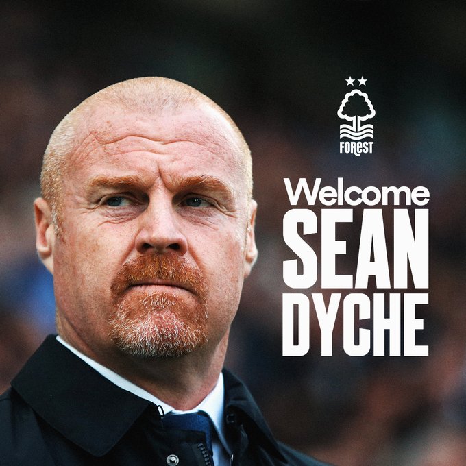 Portrait of Sean Dyche a bald man with a mustache wearing a dark suit and blue tie looking directly at the viewer against a blurred stadium background. Text overlay reads Welcome Sean Dyche in white bold letters. Nottingham Forest club logo featuring two stars and a tree is positioned in the top right corner.