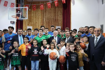 First image shows a man in a suit speaking at a podium during the opening ceremony with a large screen displaying Turkish text Yakınca Gençlik Merkezi and Tenis Kortu Açılış Töreni in Malatya along with microphones and banners. Second image depicts the same man in a suit holding a ribbon with children including boys and girls some wearing headscarves and casual clothes surrounded by adults in formal attire cutting the ribbon in front of a stage. Third image captures a group of young basketball players in green jerseys and others in casual clothes with adults including suited officials jumping to shoot a basketball into a hoop inside a gymnasium with Turkish flags and banners on the walls. Fourth image features a large group photo of children in sports jerseys holding basketballs adults in suits and formal wear posing together in a hall with wooden paneling red curtains a basketball hoop and Turkish flags in the background.