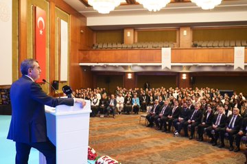 First image shows a man in a suit standing at a blue podium with a microphone, speaking in front of a large screen displaying Turkish flags, the text 2024 YLSY Bursiyerleri Vizyon ve Farkındalık Eğitimi Programı 3-5 Temmuz Ankara, and official seals. Second image depicts the same man in a dark suit gesturing at a white podium with a microphone in an ornate hall with chandeliers, Turkish flags on walls, and a seated audience of men and women in formal attire listening attentively. Third image features a large group photo of diverse men and women in business attire standing together on a stage with a blue banner reading 2024 YLSY Bursiyerleri, flanked by large Turkish flags and portraits.