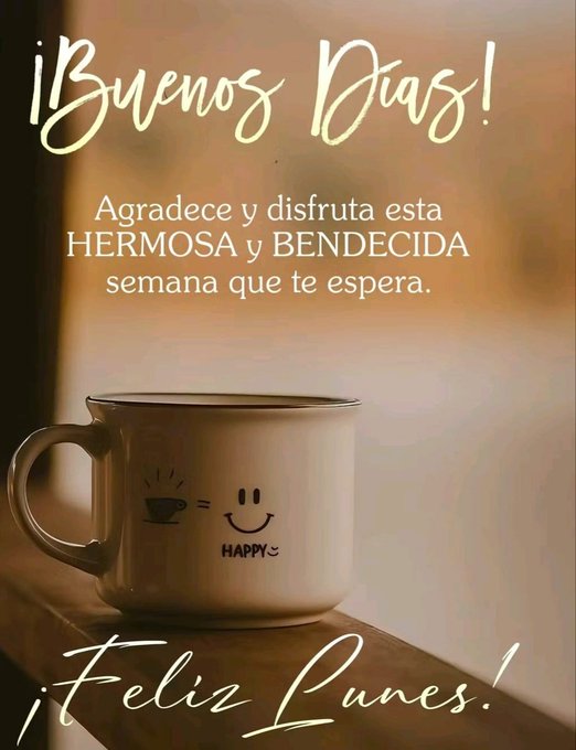 A white ceramic mug with a simple smiling face drawn on it and the word Happy printed below sits on a wooden surface. The mug holds a hot beverage with steam rising. Warm sunlight filters through a nearby window creating a soft glow. Overlaid text in Spanish reads Buenos dias with decorative elements and a message to appreciate and enjoy the beautiful blessed week ahead. At the bottom Feliz Lunes appears in playful font.