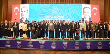 İlk görüntüde bir adam kürsüde konuşma yapıyor, arkasında Nevşehir Hacı Bektaş Veli Üniversitesi logosu ve 2024 YLSY Bursiyerleri Vizyon ve Farkındalık Eğitimi Programı yazısı var, kürsüde Semih Aktekin ve Ankara 3-7 Kasım yazıları görülüyor. İkinci görüntüde mavi arka planda Türk bayrakları ve 2024 YLSY Vizyon ve Farkındalık Programı yazısı, sahne önünde oturmuş bir grup insan ve konuşmacılar var. Üçüncü görüntüde geniş bir salonda mavi ekranlı sahne, Türk bayrakları ve kalabalık bir dinleyici grubu koltuklarda oturuyor. Dördüncü görüntüde grup fotoğrafı, çeşitli kıyafetli erkek ve kadınlar sahnede poz veriyor, arka planda mavi ekran ve Türk bayrakları ile program yazısı.