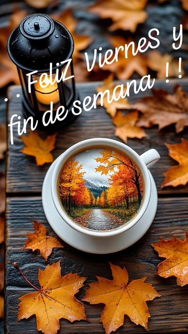 A white coffee cup sits on a dark wooden surface with scattered orange autumn leaves. Inside the cup, a detailed painting shows a winding path through a forest of tall trees with vibrant orange and yellow foliage under a blue sky. A black lantern with a lit candle flame is positioned to the left, casting soft light. Text overlays read Feliz Viernes y fin de semana in white cursive font.