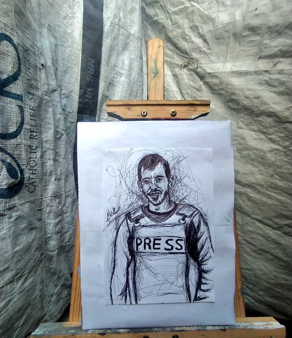 Charcoal sketch on paper mounted on a wooden easel, depicting a man with curly hair and a mustache smiling, wearing a vest labeled PRESS over a long-sleeve shirt, set against a background of gray tarpaulin with partial text Catholic Relief visible and wooden supports.