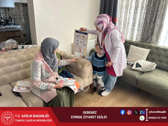 First image shows a man in professional attire sitting on a beige sofa in a living room with wooden floor and large windows holding papers while a woman in headscarf and coat sits beside him with a young boy in green vest on her lap and a toddler in blue nearby with pillows and curtains in background. Second image depicts a nurse in pink scrubs and headscarf standing in a similar living room holding a poster with diagrams pointing to it while a woman in headscarf and coat sits on sofa with papers and a child in blue outfit beside her with beige sofa gray pillows and window views.