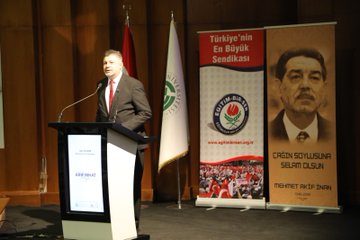 First image shows a man in a dark suit speaking at a podium with microphone in a conference room featuring banners for Turkiyenin En Buyuk Sendikasi and Arif Nihat Asya Nihai Asya alongside the Eğitim-Bir-Sen logo and a screen displaying Vefatının 50 Yılı. Second image depicts a man in a suit at a podium with a large projected portrait of Arif Nihat Asya wearing glasses and a red tie next to banners for Ercan Solusan and Arif Nihat. Third image captures a man in a gray suit speaking at a podium with Turkish and another flag banners for Turkiyenin En Buyuk Sendikasi and Eğitim-Bir-Sen plus a portrait of Arif Nihat Asya and text for Çukurova Solusan Mehmet Akif. Fourth image displays a large group of people including men and women in formal attire standing on a stage with a Turkish flag table with cups and microphones in a hall setting.