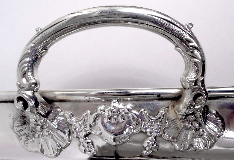 German Classical 800 silver tea tray, c. 1920. Rectangular and chamfered; shell-mounted leaf-wrapped end handles. Scallop shells in applied scroll and pendant flower surrounds applied to shoulder. Armorial engraved in well. Marks; no. 152185. Item#CA399

nelsonandnelsonantiques.com/items/1509596/…