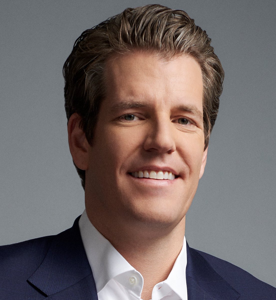 Tyler Winklevoss in a sharp suit, smiling confidently