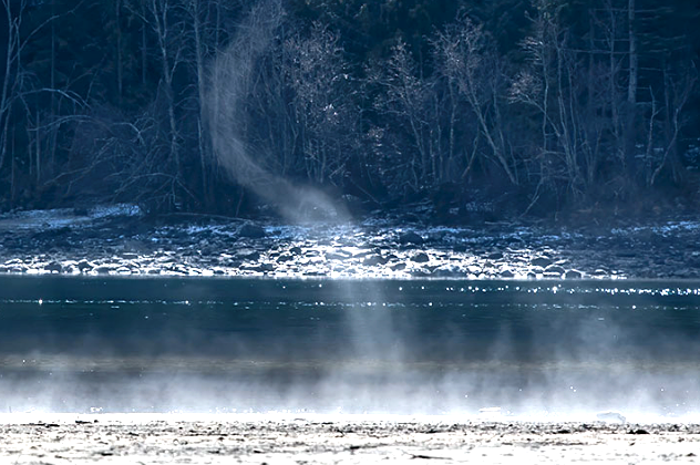 geologyBits's tweet photo. 🟥 ⛅️ A steam devil
Is a rare, transient vortex phenomenon resembling a miniature whirlwind or dust devil but composed of condensed water vapor (steam) rather than dust or debris.    

❤️ 🔁 #SteamDevil #ArcticSeaSmoke                                                                  

🎞️ @pawleewurx
▶️ Forming a small, rotating column typically 1-2 meters (3-6 feet) in diameter and 3-10 meters (10-33 feet) tall.

It appears as a faint, swirling plume of white or grayish fog against a cold backdrop, often twisting erratically with low rotational speeds (under 10-20 mph) and a short lifespan of seconds to minutes, dissipating quickly upon contact with drier air.

Steam devils are most commonly observed in winter over open water bodies like lakes, rivers, or wetlands where steam fog (arctic sea smoke) is prevalent, or near geothermal features such as geysers and hot springs in areas like Yellowstone National Park or Lake Texoma.

Unlike more intense vortices, they pose no significant hazard but serve as visual indicators of strong temperature contrasts between air and surface, enhancing atmospheric mixing and heat transfer.

▶️ Steam devils arise from the interaction of cold, dry air with a much warmer underlying surface, typically in stable but slightly unstable boundary layers during calm to light wind conditions.

When frigid air (often below freezing) flows over heated water or steam-emitting vents, at temperature differentials exceeding 10-20°C (18-36°F), rapid evaporation occurs, saturating the air and causing condensation into visible steam fog as the moist parcels rise buoyantly due to their lower density.

This upward motion creates localized low-pressure zones at the surface; if ambient wind shear or minor turbulence introduces rotation (via horizontal vorticity tilting into the vertical), the rising steam organizes into a self-sustaining vortex, drawing in surrounding fog and amplifying the spin through conservation of angular momentum.

Akin to the formation of dust devils but driven by latent heat release from condensation rather than solar heating of the ground.

The process, which can spawn multiple devils in clusters, lasts only briefly as the vortex entrains drier air aloft, cooling and dispersing the steam.

Analogous phenomena include fire devils over wildfires, highlighting thermal instability's role in mesoscale vorticity generation.