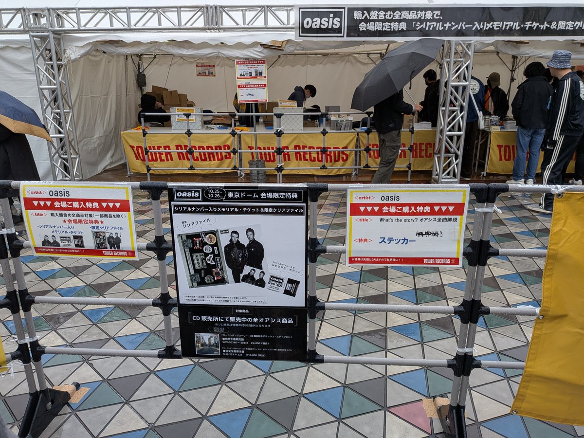 zep1980's tweet photo. オアシス　東京ドーム初日は小雨ですが風があるので濡れますね。物販はスムーズに流れています。ダメ元の当日券の列が結構伸びてます。 https://t.co/eg3MpWe1TI