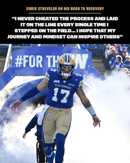 Athlete Chris Streveler in Winnipeg Blue Bombers blue jersey number 13 and gold pants stands on football field with helmet on arms extended wearing pads and cleats amid blue smoke with team banners overhead and blurred figures in background.