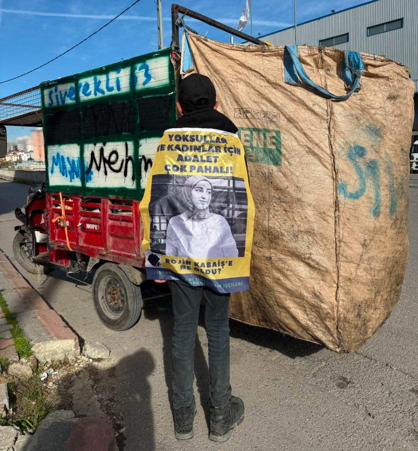 Bir geri dönüşüm işçisinin Rojin Kabaiş için sırtına astığı pankart:

"Yoksullar ve kadınlar için adalet çok pahalı!"