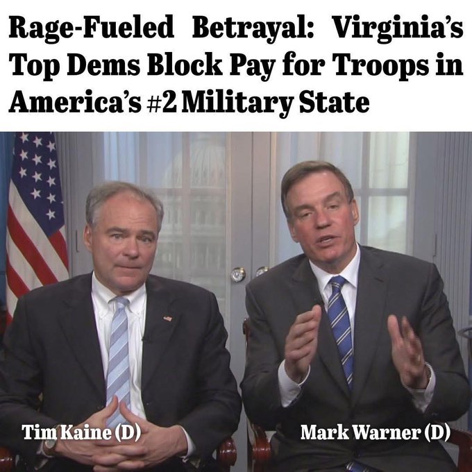 Two men in suits and ties sit side by side in front of a blue curtain with American flags on either side. The man on the left has short gray hair, wears a light blue tie, and gestures with his hands. The man on the right has short brown hair, wears a blue tie, and sits with hands clasped. Text overlay reads Rage-Fueled Betrayal: Virginias Top Dems Block Pay for Troops in Americas #2 Military State with labels Tim Kaine (D) below the left man and Mark Warner (D) below the right man.