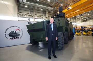 First image shows a man in dark suit and blue tie standing at a white podium with red Turkish emblem, speaking into microphones, with green military tank in background and barriers. Second image depicts the same man in suit standing beside large green armored vehicle labeled Altay in industrial hall with overhead cranes and Turkish flag emblem on wall. Third image features group of men in suits and one in yellow helmet with blue uniform examining interior of green machinery platform in factory setting with railings and equipment. Fourth image displays line of suited men including one in white headwear cutting ribbon at event stage with screens showing leaders, Altay logos, and floral decorations.