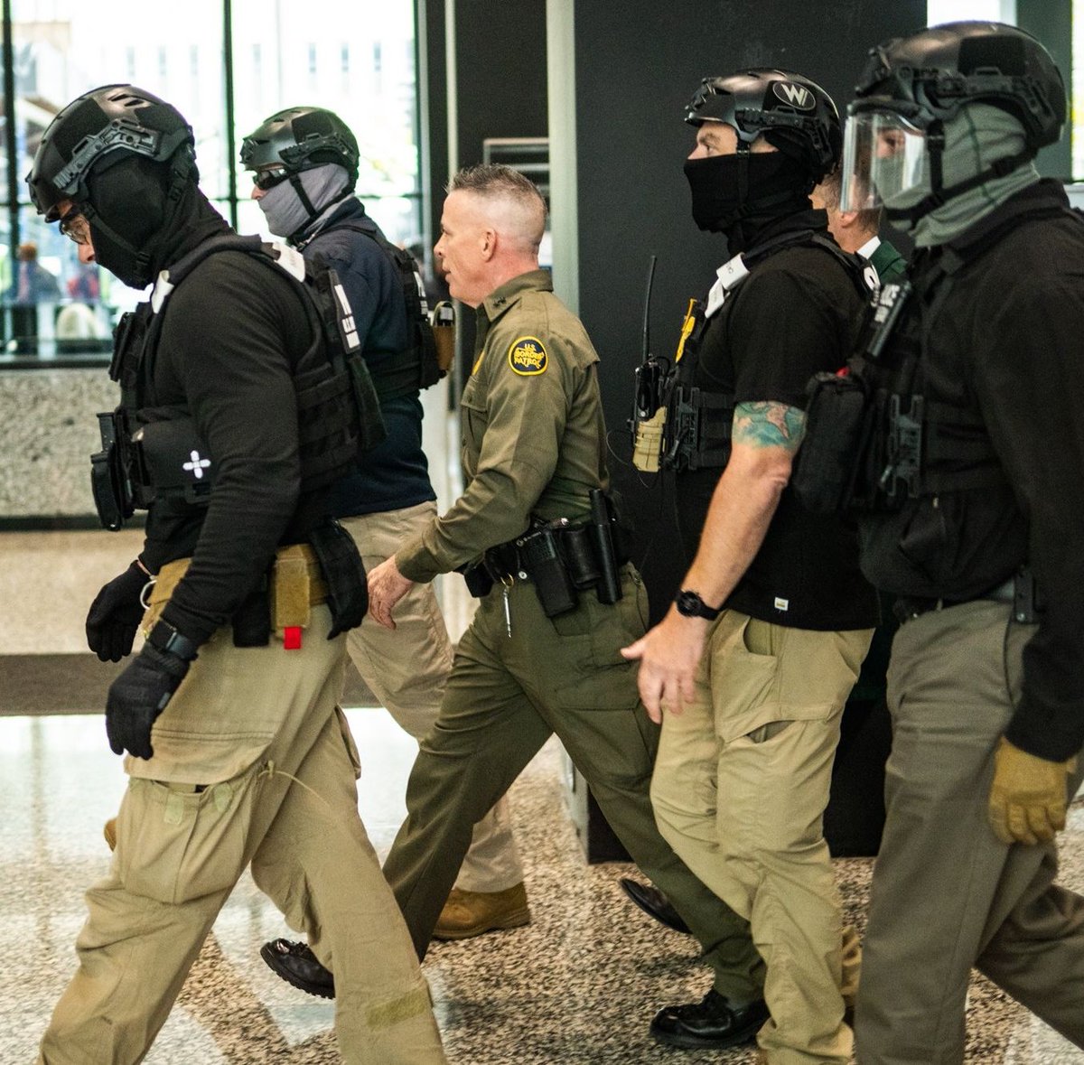 The little oompa-loompa man in the middle is Border Patrol Cmdr Gregory Bovino called in front of the judge for using excessive force in Chicago against peaceful protestors and U.S. citizens.  I didn't know they made Border Patrol uniforms that small.