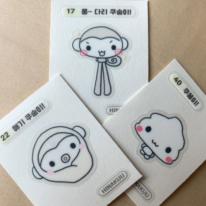 First image shows several pink plastic-wrapped packages of snack buns with chocolate filling, each featuring a cute white monkey character with rosy cheeks on a blue background, text in Korean reading something like chocolate-filled bun product name and details, a small illustration of the bun on a plate below the monkey, and nutritional labels on the side. Second image displays four white sticker sheets from a collectible series labeled HinaKku, including numbered cards 17, 40, 22 with line-drawn monkeys in playful poses like standing tall with curly tail, sitting with surprised expression, and a puffy dumpling character with blush.