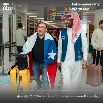 First image shows two men in Biban entrepreneurship vests, one wearing a blue cap and black jacket holding a black suitcase, the other in white thobe and red headscarf standing near UN Tourism and Qatar Airways banners in an airport terminal with other travelers and luggage. Second image depicts a man in red headscarf and blue vest conversing with a woman in black top and colorful skirt carrying a beige bag, near airport signage and other passengers. Third image features a man in glasses and black shirt holding a Texas flag next to a man in blue vest and white thobe carrying a yellow suitcase, with airport displays and diverse individuals in background. Fourth image captures a man in maroon sweater holding a yellow suitcase talking to a man in red headscarf and blue vest, surrounded by men in various attire near flight information screens in a modern airport setting. All images include Biban forum logos, World Cup for Entrepreneurship text in Arabic and English, and sponsor mentions like SME Bank.