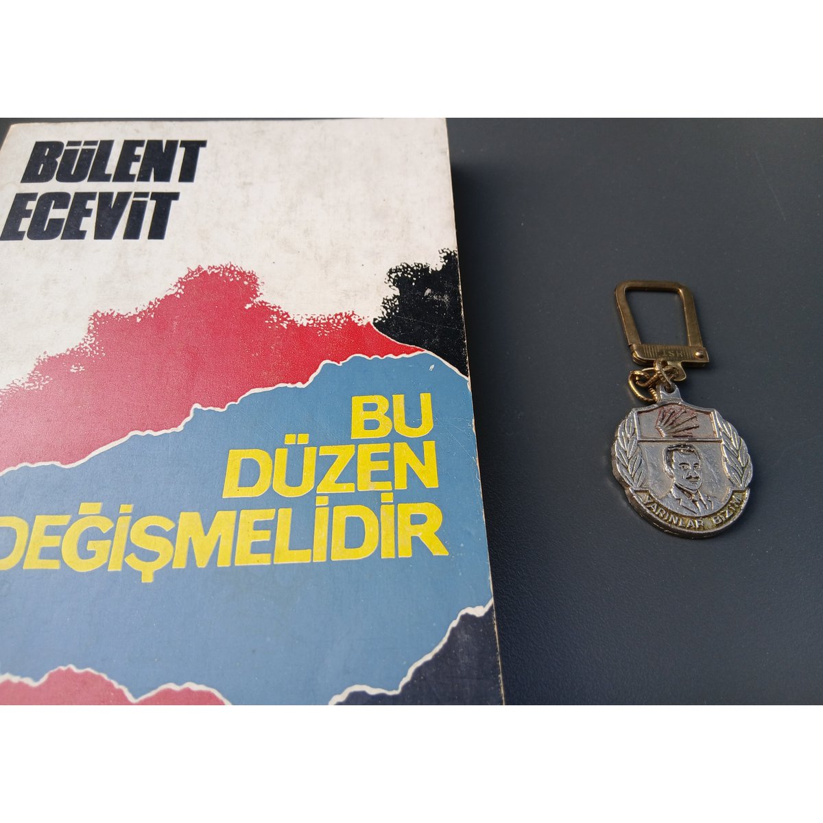 Koleksiyonculuk işlerine devam:)Bugün yapacağım Bülent Ecevit konuşması için malzemeyle geldim."Bu Düzen Değişmelidir"in ilk baskısı. Ama daha ilginç olanı, Rahşan Ecevit partiye gelir sağlamak için amblemli çakmak, anahtarlık vs. satışı işini akıl etmiş.Bu da Ecevit anahtarlığı.
