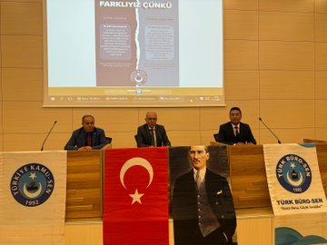 First image shows a man in a dark suit and tie standing at a wooden podium with microphones, gesturing with both hands outstretched, in front of a light wooden wall and two Turkish flags on poles. Second image depicts a conference room with a projection screen displaying a title FARKLILIK CUNKU and images of documents and a logo, three men in suits seated at a table with microphones, Turkish flags and banners for Turk Buro-Sen and Turkiye Kamu-Sen on the table and walls, a large portrait of Mustafa Kemal Ataturk. Third image features a modern building projected on a screen behind a podium, several men in suits seated and one speaking at the podium with a microphone, banners with eye symbols and Turkish flags on wooden tables. Fourth image shows a large group of about 30 people mostly men in suits standing in rows on a stage with blue backdrop, some holding documents, in a formal assembly setting.