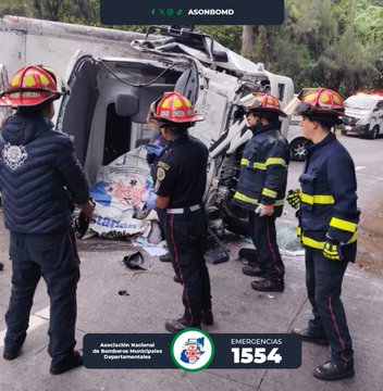 First image shows several firefighters in red helmets and uniforms attending to a severely damaged white truck cab overturned on a roadside with debris scattered around. Responders are positioned around the wreckage some holding tools and wearing gloves while a police officer stands nearby. The scene is on a paved road with greenery in the background and includes a logo for Asociacion Nacional de Bomberos with emergency line 1554 at the bottom. Second image depicts firefighters examining the interior of the same wrecked truck cab with one responder leaning inside and others standing around holding bags and tools. The vehicle is tilted with broken glass and damaged doors visible and the same emergency logo present at the bottom.