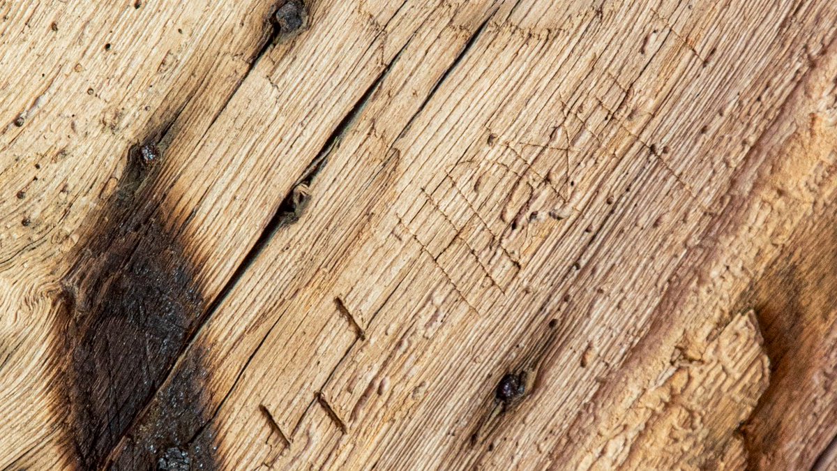 I took photos of some burn marks (like candle marks) that were all over the base of the timbers - but it wasn't until I zoomed in on my computer and saw minute symbols, barely visible to the eye, delicately cut into the wood next to the marks.