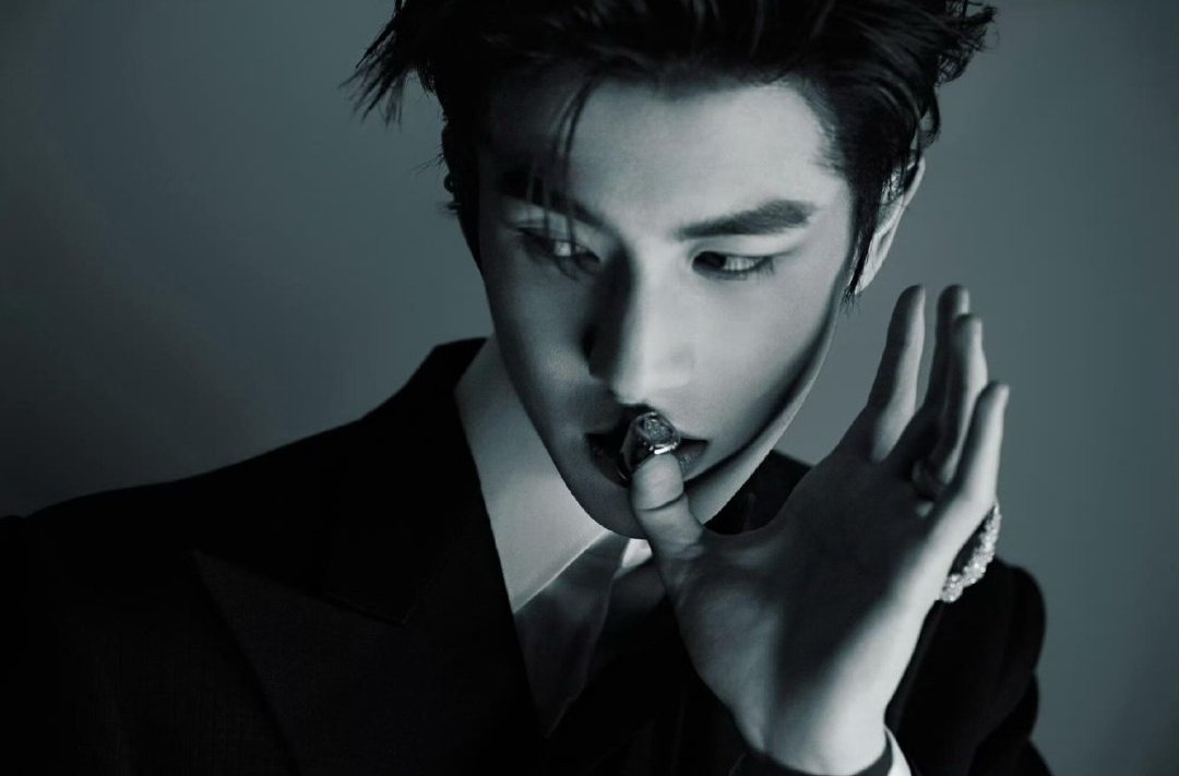 A symphony of elegance wrapped in monochrome silence he stands like a shadow carved from dusk. 
The tailored suit fits like a whispered secret, structured yet soft, its black fabric drinking in the faint light that dares to touch it.